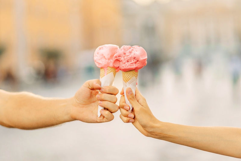 Men's and women's hands hold bright ice cream cone. hands holding ice cream cone. summertime. 
