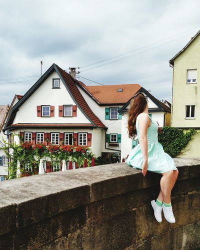Woman standing outside house against sky