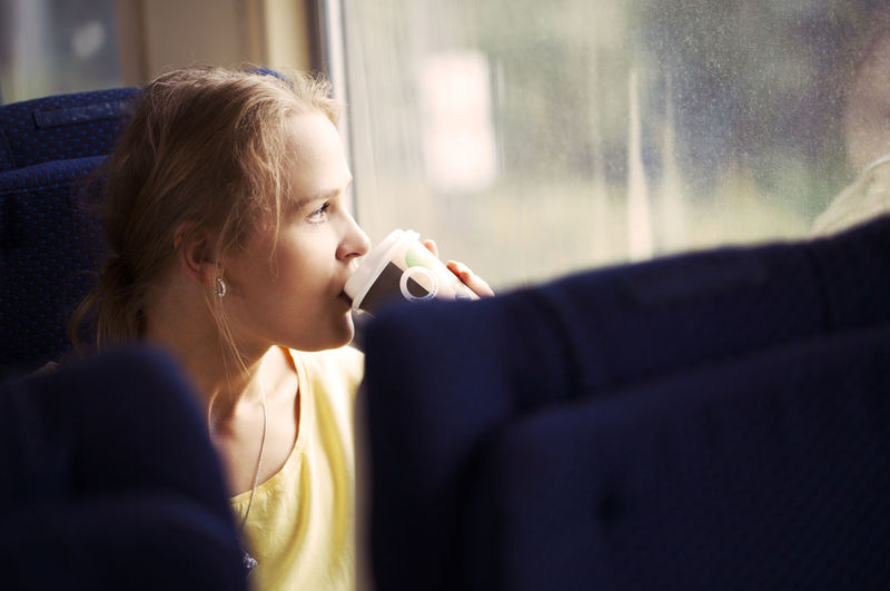 Young woman drinking in train