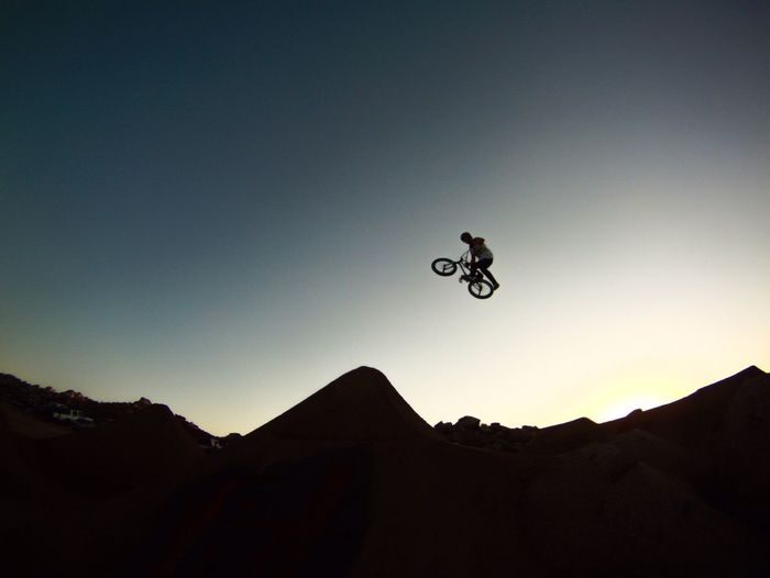 Low angle view of bmx biker against blue sky