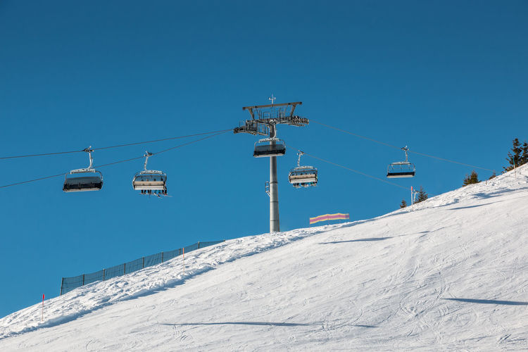 Low angle view of ski lift against clear blue sky