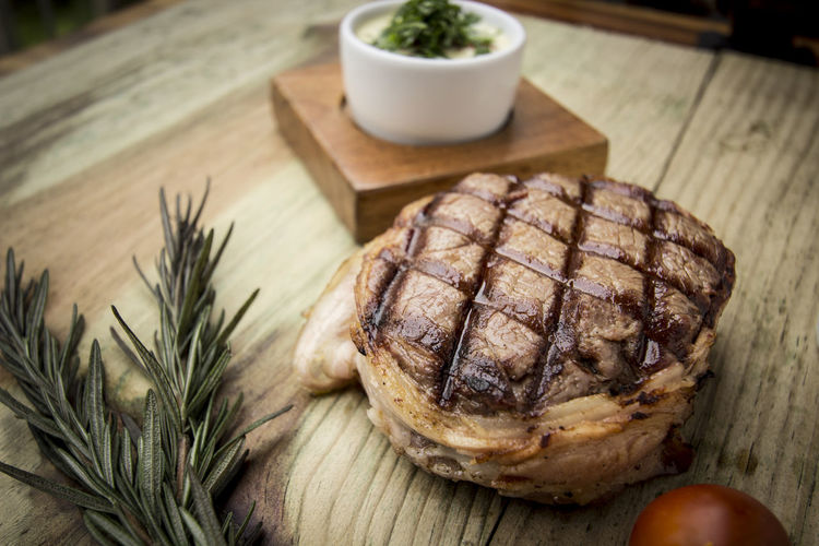 Close-up of tenderloin steak by rosemary on wooden table