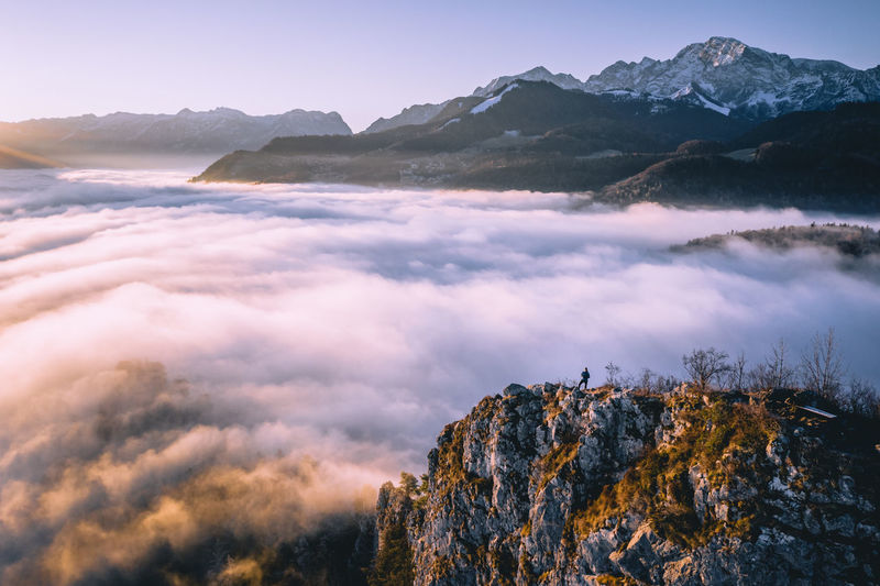 High angle view of man standing on mountain ridge rising above the clouds, hallein, austria