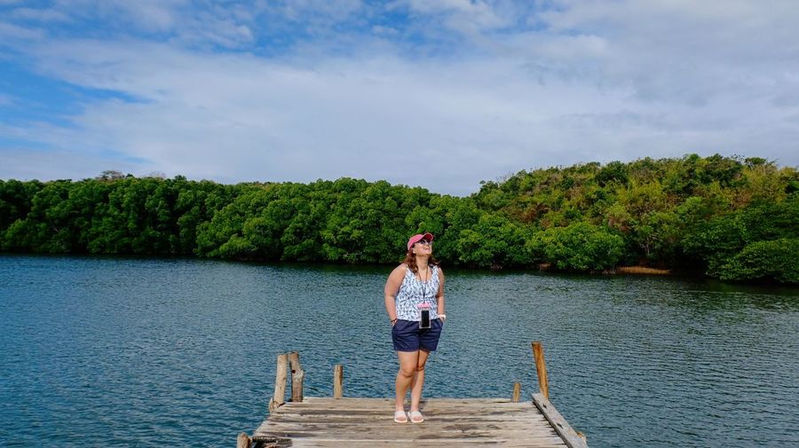 Full length of woman standing on pier over lake against sky