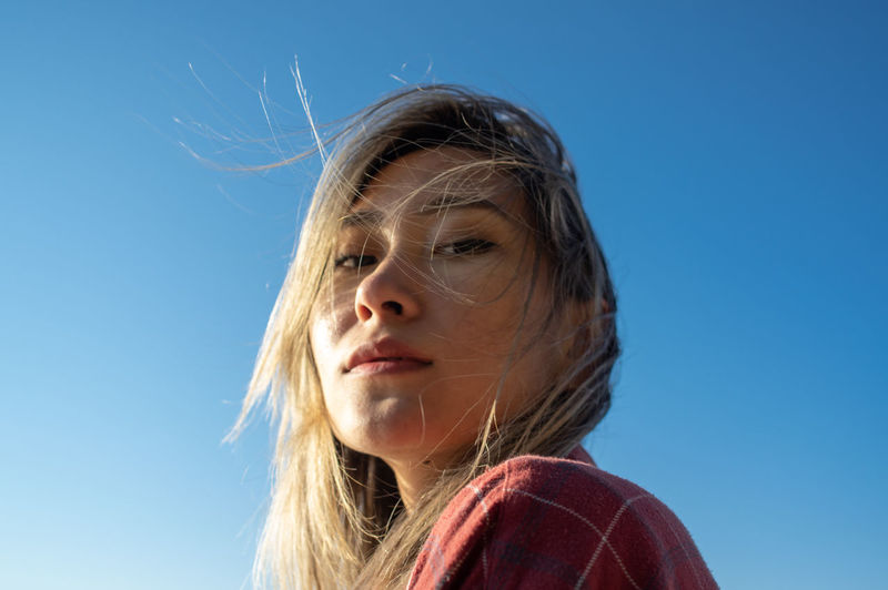 Close-up portrait of woman against blue sky