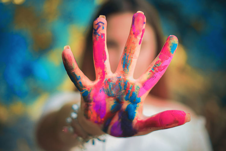 Close-up portrait of young woman showing colored hand while celebrating holi