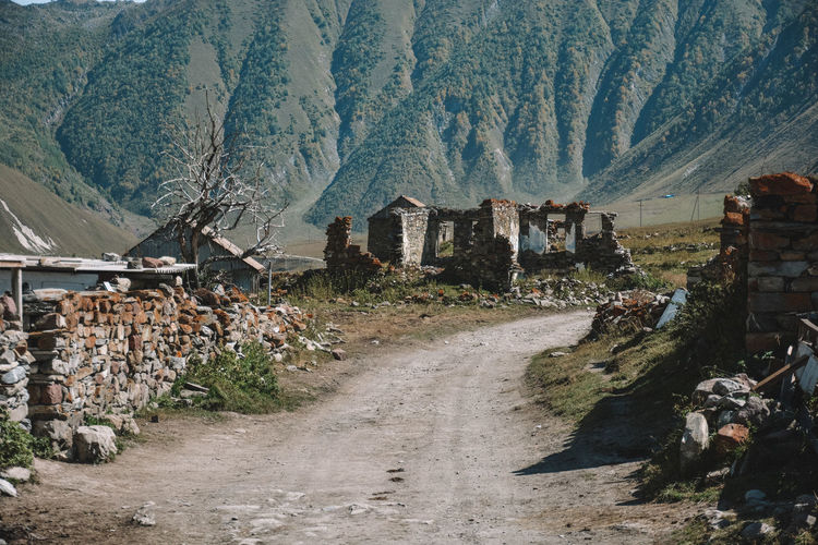 Dirt road amidst buildings and mountains