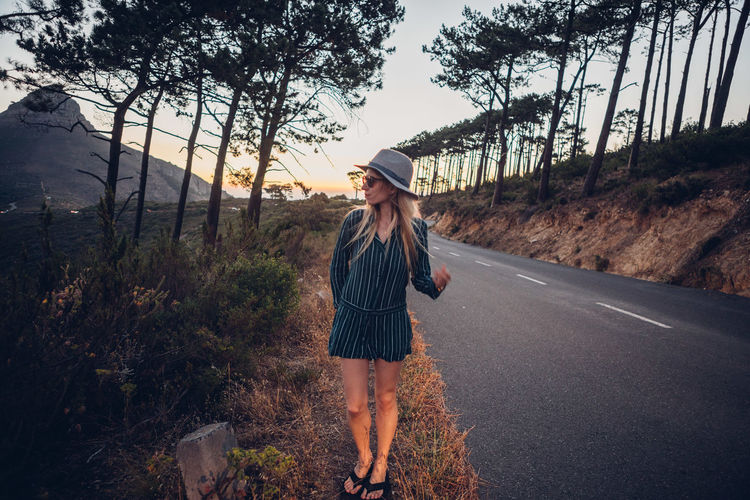 Woman standing on roadside during sunset