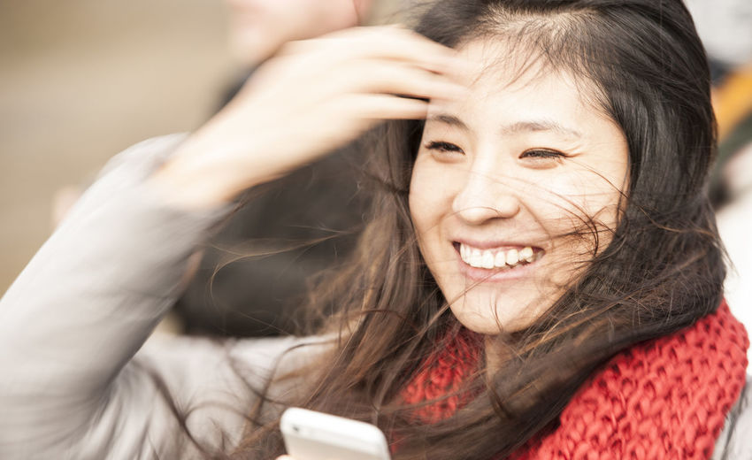 Beautiful woman looking at her cellphone in windy weather