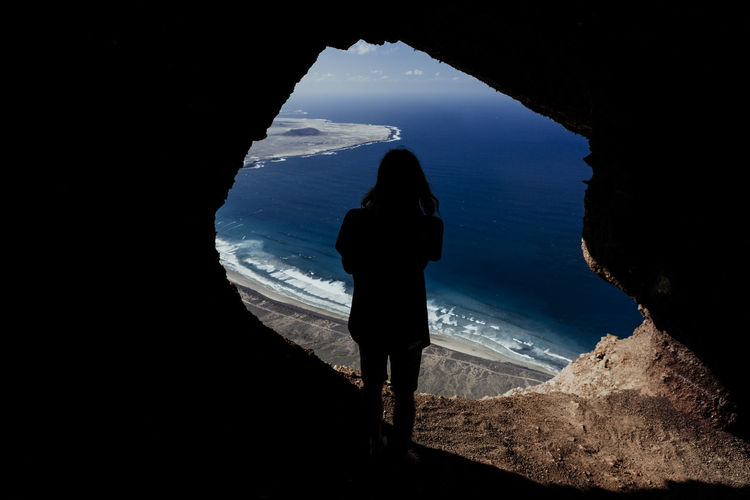 Silhouette of a man from a cave in the cliffs of famara in lanzarote