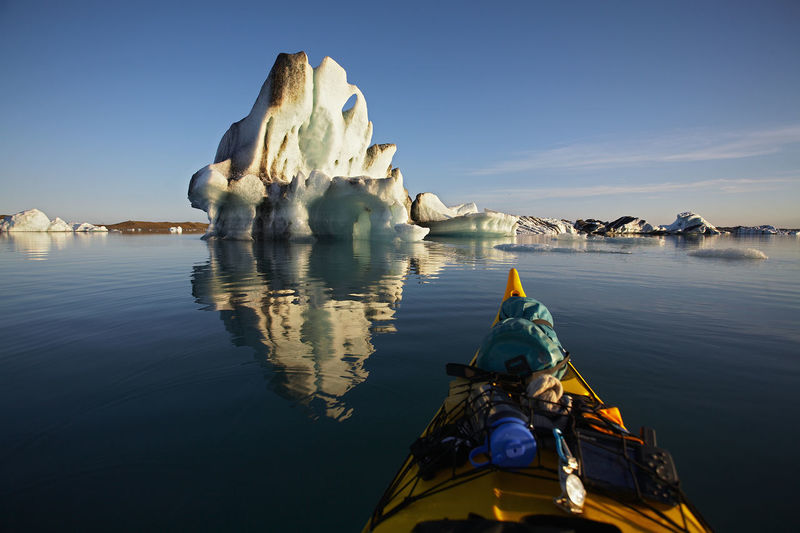Stern of a sea kayak floating towards an iceberg on a glacier lagoon