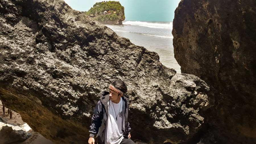 Young man standing on rock at sea