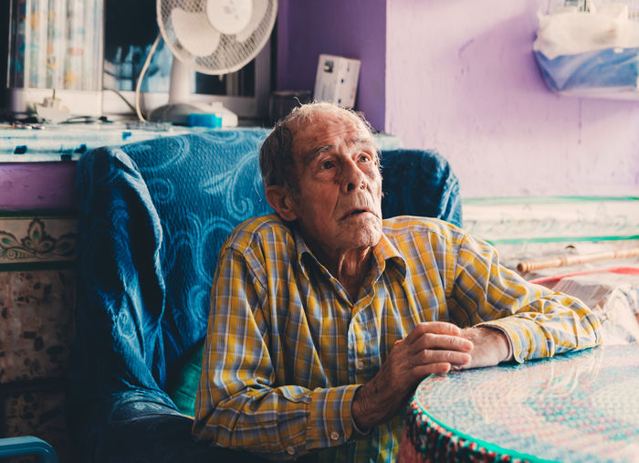 Portrait of man sitting on bed at home