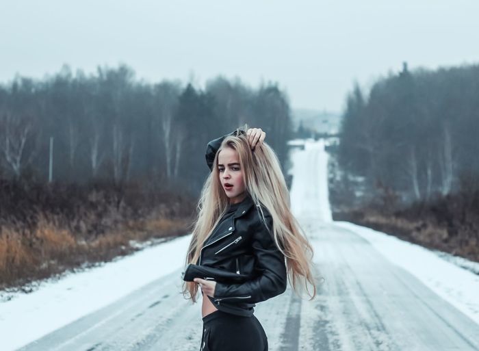 Young woman posing while standing on snow covered road