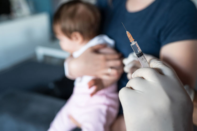 Cropped hand of doctor holding syringe for vaccination
