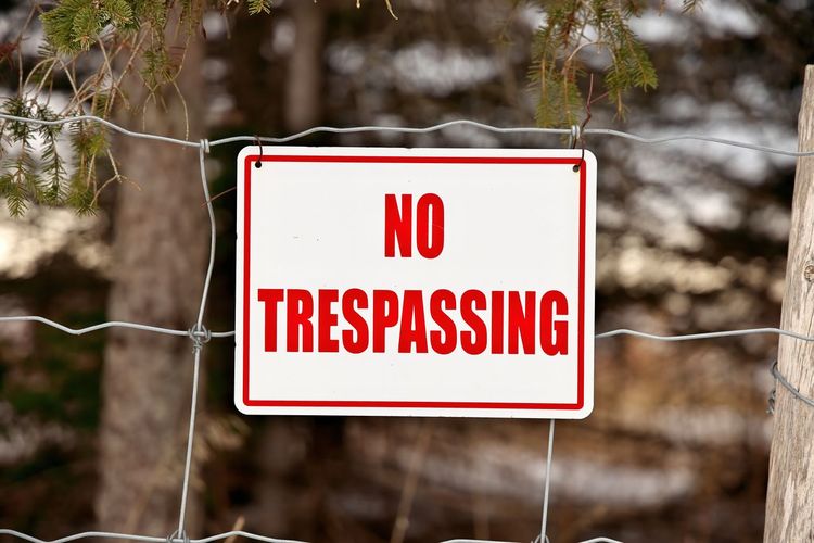 No trespassing sign posted on a wire fence in a rural setting. high quality photo