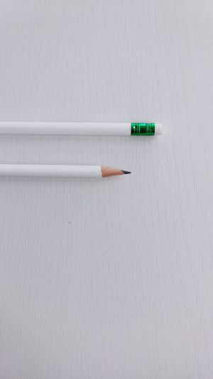 Directly above shot of pencils with eraser on white table
