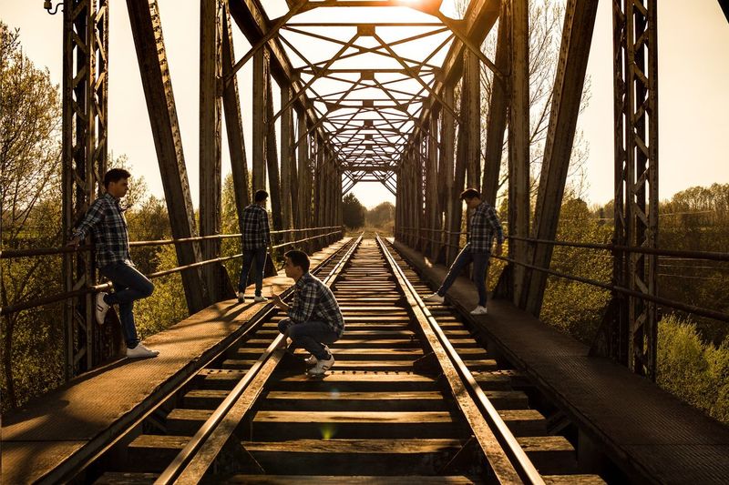 Multiple image of man on railroad bridge against sky