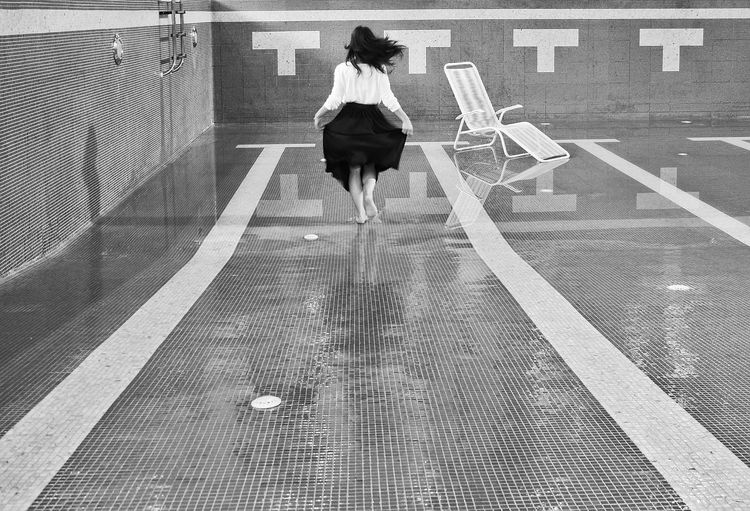 Rear view of woman walking by swimming pool