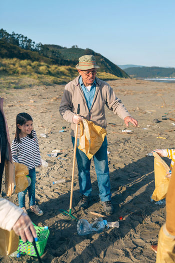 Grandfather guiding family while cleaning beach