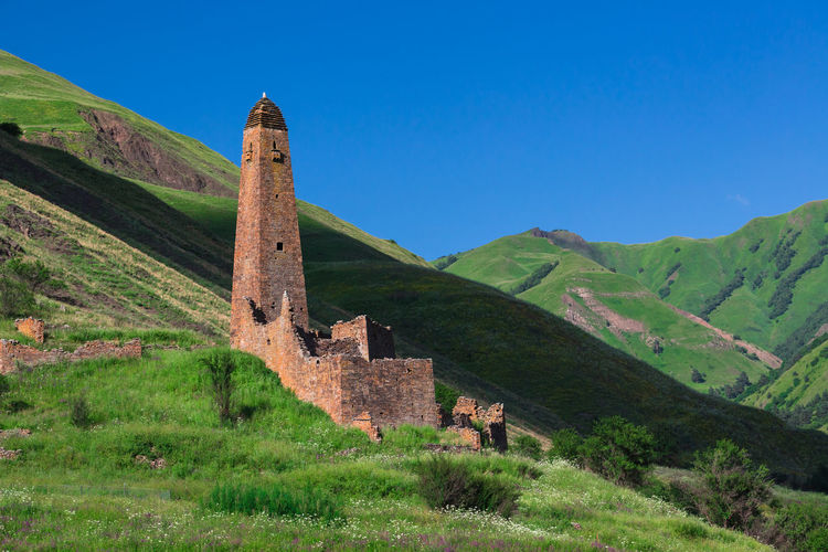 Built structure on landscape against clear blue sky