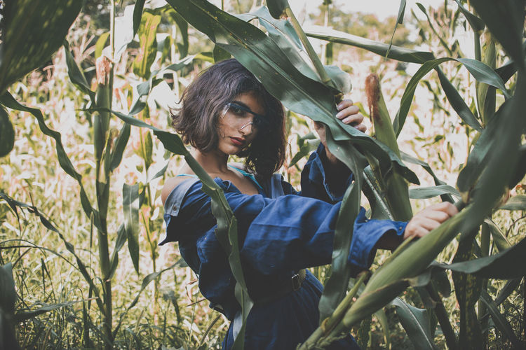 Portrait of young woman standing amidst plants
