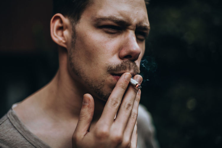 Young man smoking cigarette outdoors
