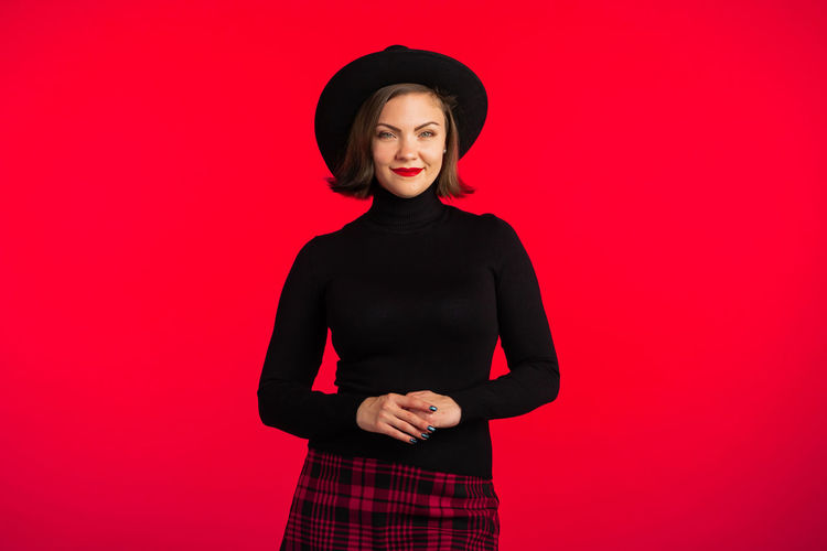 Portrait of smiling young woman against red background