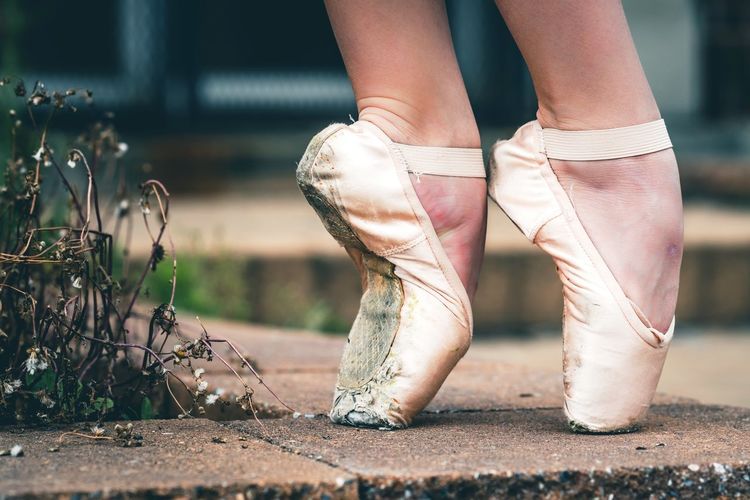 Low section of ballet dancer tiptoeing on footpath