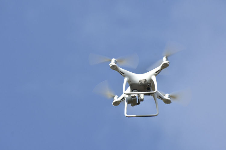 Low angle view of drone flying against clear sky