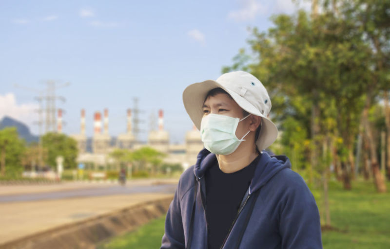 Man wearing mask and hat standing in park