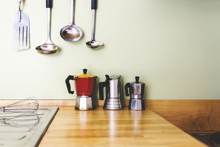 Coffee makers on table by utensils in kitchen