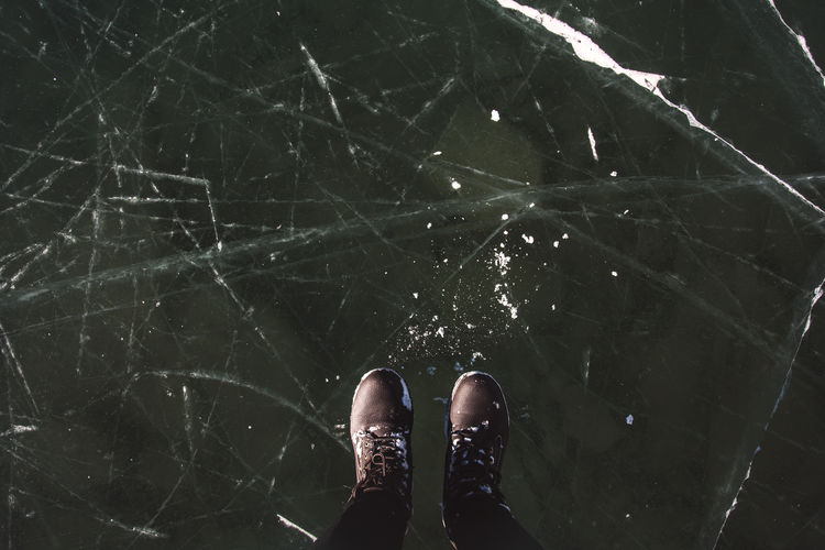 Low section of person standing on frozen lake
