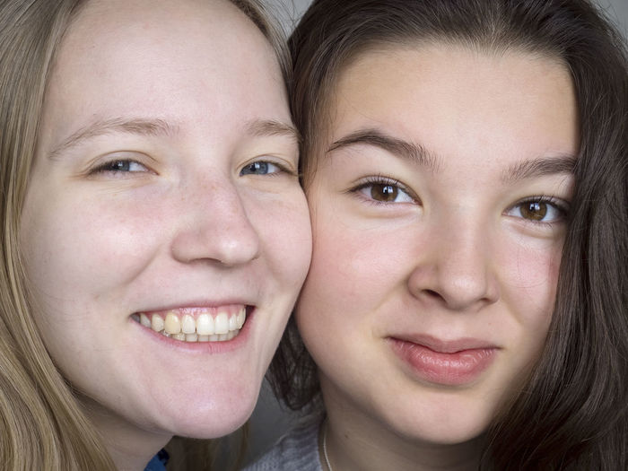 Close-up portrait of smiling sisters