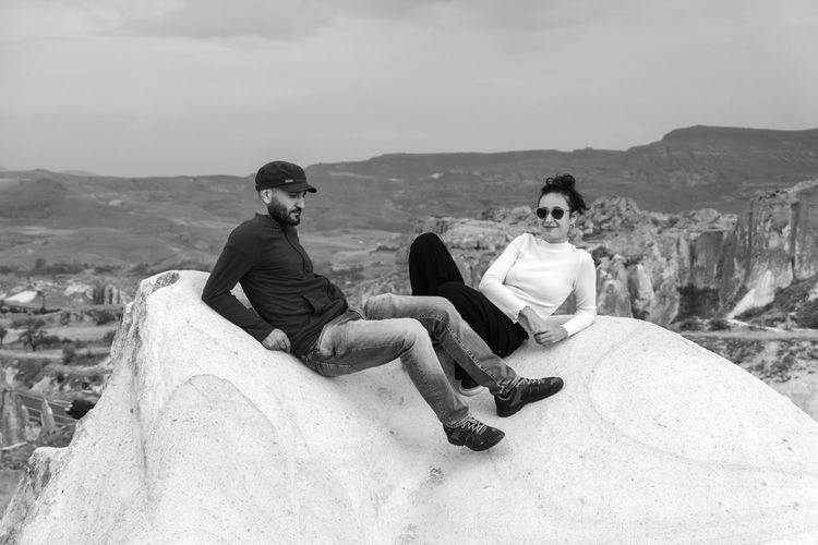 Men sitting on rock against sky