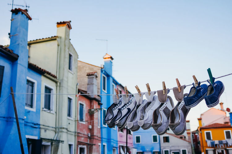 Low angle view of shoes drying on clothesline against building sky