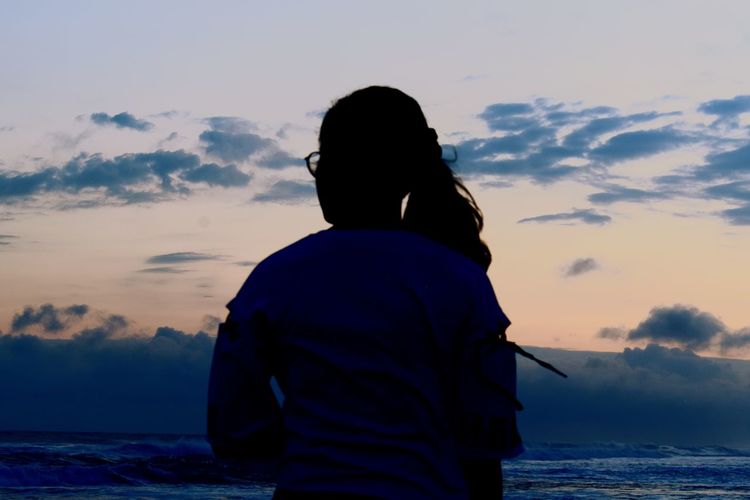 Rear view of silhouette man looking at sea against sky