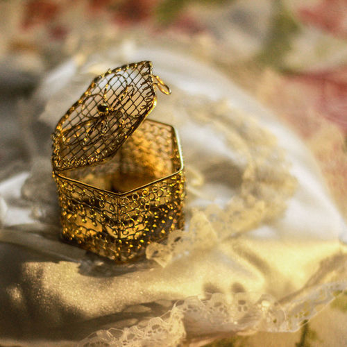 Close-up of golden container on lace fabric