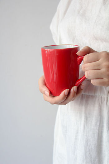 Midsection of woman holding coffee against white background