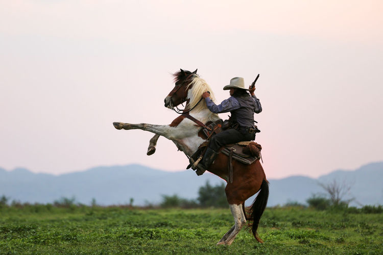 Man riding horse on land against sky