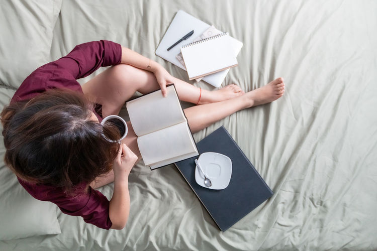 High angle view of woman using laptop on bed at home