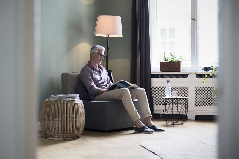 Mature man reading magazine at home