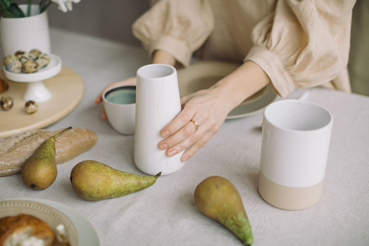 Midsection of woman with fruits having tea on table