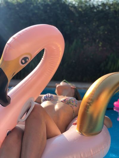 Woman in bikini relaxing on pool raft in swimming pool