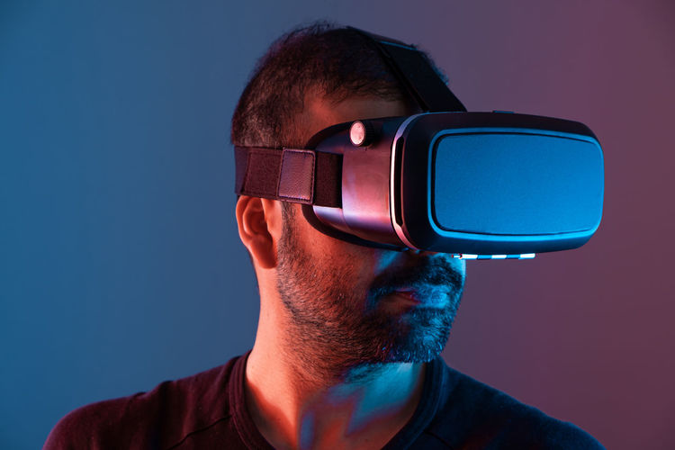 Young man in vr glasses close up portrait virtual reality in color neon light,  video gaming