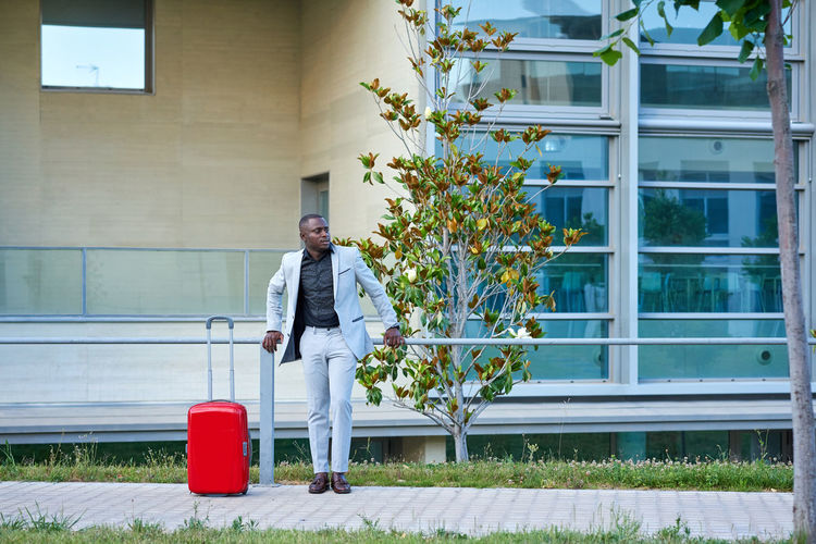 African-american in a white suit and a red suitcase. person