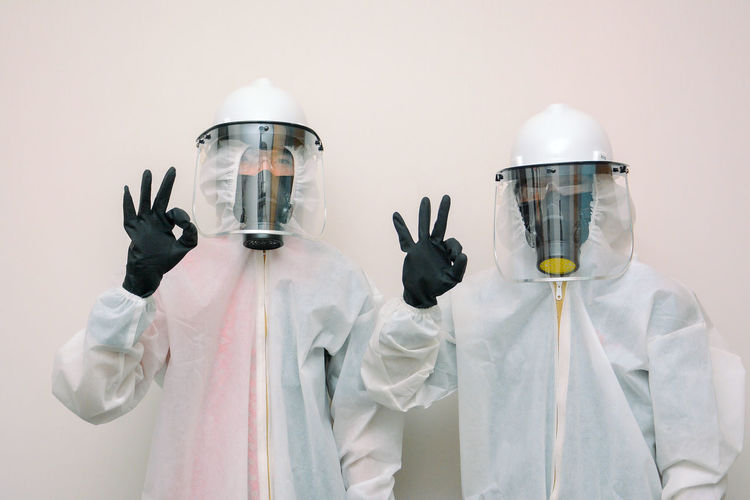 Portrait of doctor wearing protective suits standing against white background
