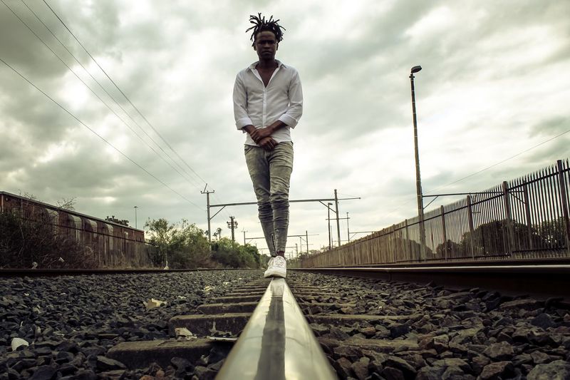 Low angle view of person standing on railroad track against sky