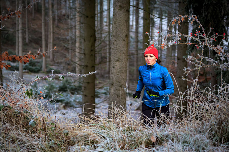 Woman jogging in forest during winter