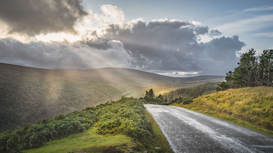 Winding road leading to lough tay called the guinness lake, dramatic sunset, wicklow, ireland